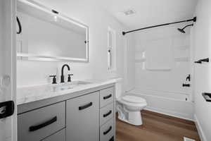 Full bathroom featuring vanity, dark wood-style flooring, and  shower combination