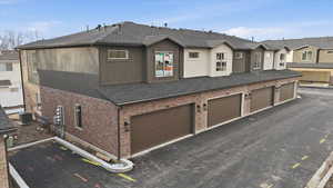 Traditional-style home with brick siding, a residential view, a shingled roof, stucco siding, and an attached garage