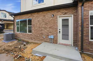 Property entrance featuring brick siding and a patio