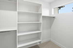Walk in closet with light colored carpet
