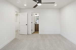 Unfurnished bedroom featuring light colored carpet, a ceiling fan, recessed lighting, and ensuite bath