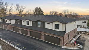 View of front of property with stucco siding, brick siding, a residential view, asphalt driveway, and an attached garage