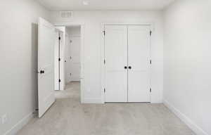 Unfurnished bedroom with light carpet and a closet