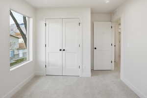 Unfurnished bedroom featuring light colored carpet and a closet