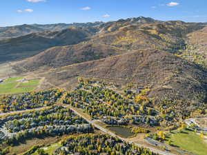 Aerial view of property and surrounding area featuring a mountainous background and nearby suburban area