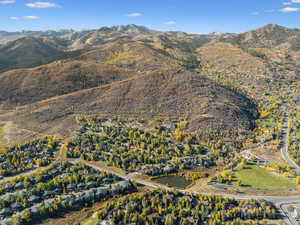 Aerial view of property and surrounding area featuring a mountainous background and nearby suburban area
