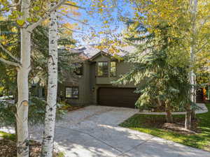 View of front of home featuring concrete driveway, a garage, and roof with shingles