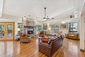 Living room with healthy amount of natural light, light wood finished floors, a ceiling fan, and lofted ceiling