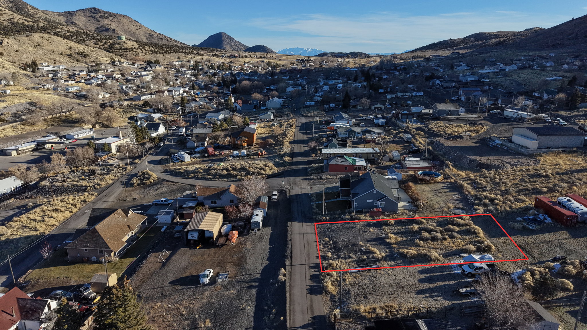Aerial perspective of suburban area with property parcel outlined and mountains