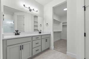 Bathroom with light colored carpet, double vanity, and a spacious closet