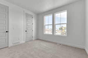 Empty room featuring light carpet and baseboards