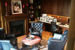 Office area featuring built in desk, light wood-style floors, a fireplace, and wood walls