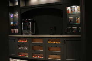 Bar area featuring glass insert cabinets, gray cabinets, and light stone countertops