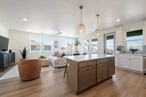 Kitchen featuring open floor plan, white cabinets, a center island, a kitchen bar, and recessed lighting