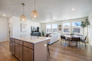Kitchen with ceiling fan, a kitchen island, recessed lighting, open floor plan, and light wood-type flooring