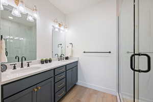 Bathroom with a stall shower, double vanity, and light wood-type flooring