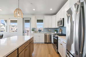 Kitchen featuring appliances with stainless steel finishes, pendant lighting, white cabinets, light wood finished floors, and recessed lighting