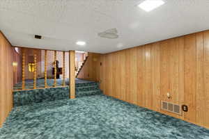 Finished below grade area with wood walls, carpet flooring, and stairs