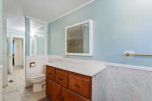 Full bathroom with tile walls, light tile patterned floors, ornamental molding, a wainscoted wall, and a shower with shower curtain