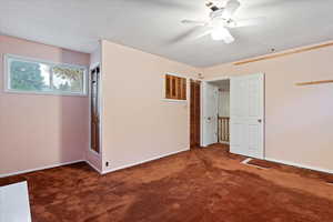 Unfurnished bedroom with dark carpet, ceiling fan, and a closet
