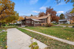 View of side of property featuring a chimney, a yard, and covered porch