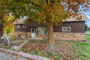 View of front facade with board and batten siding, brick siding, and a shingled roof