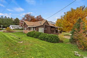 View of home's exterior featuring a lawn, stone siding, and covered porch