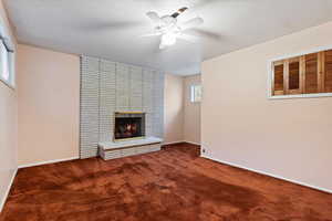 Unfurnished living room featuring carpet, a fireplace, and a ceiling fan