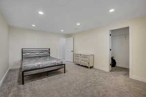 Bedroom with a spacious closet, recessed lighting, and light colored carpet