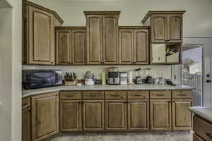Kitchen featuring light countertops, black microwave, and brown cabinets