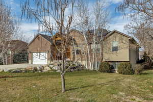 View of front of house featuring a front lawn, driveway, brick siding, an attached garage, and stucco siding