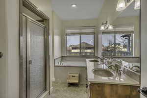 Full bath featuring double vanity, a shower stall, a garden tub, and light tile patterned floors