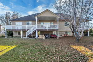 Rear view of house with a deck, stairs, and a yard