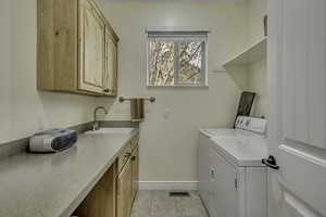 Laundry room with cabinet space, washing machine and clothes dryer, and light tile patterned floors
