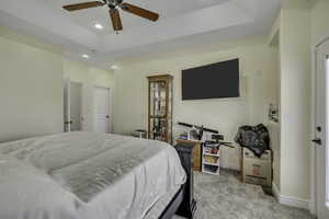 Bedroom with a tray ceiling, light colored carpet, a ceiling fan, and recessed lighting