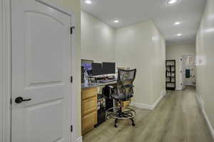 Office with built in desk, recessed lighting, and light wood-style floors