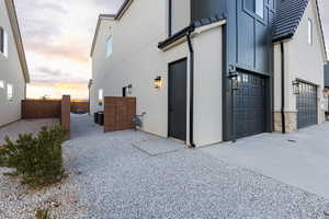 Property exterior at dusk with a garage, a fenced backyard, stucco siding, board and batten siding, and driveway