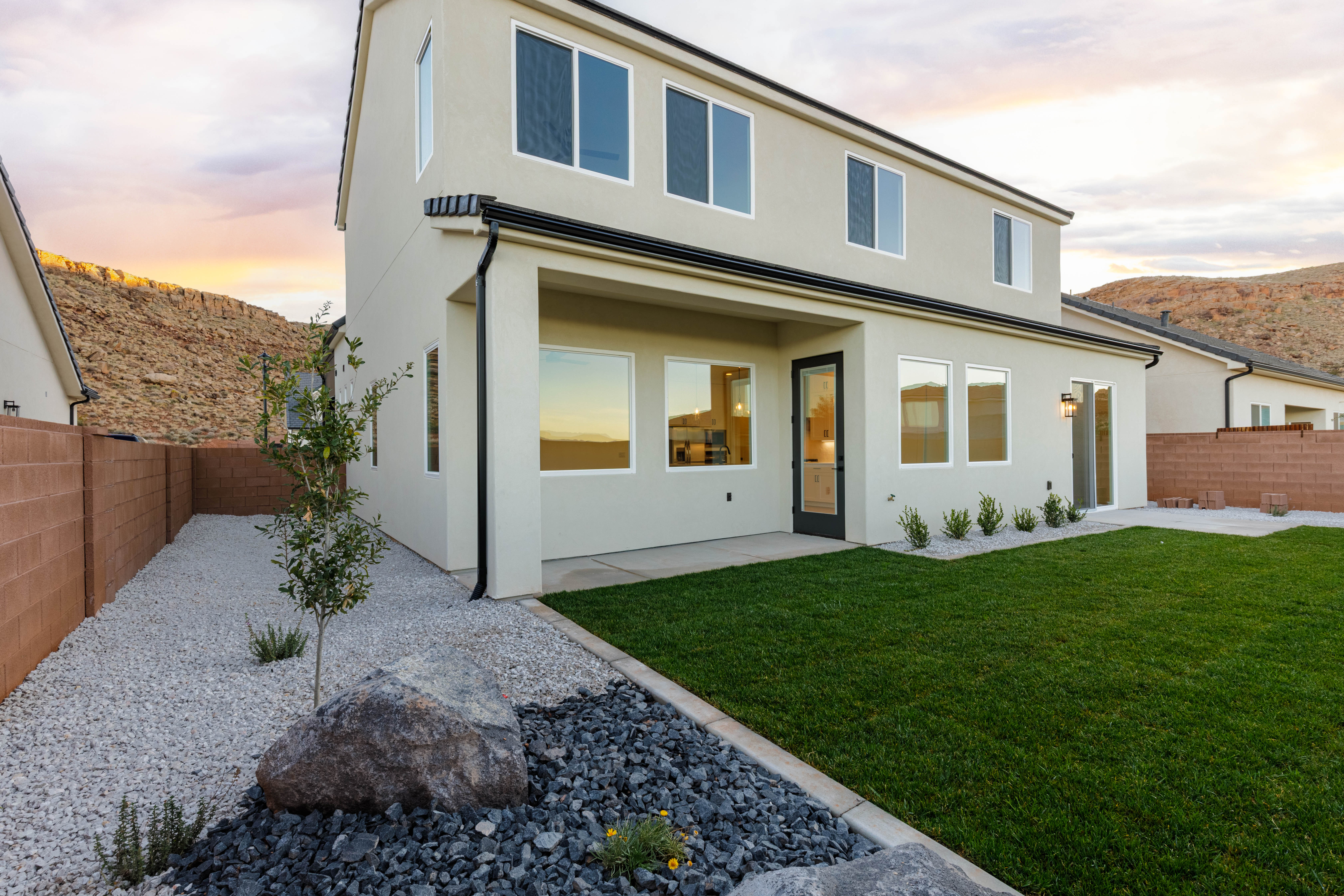 Back of property at dusk with a fenced backyard and stucco siding