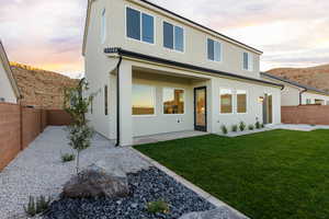 Back of property at dusk with a fenced backyard and stucco siding