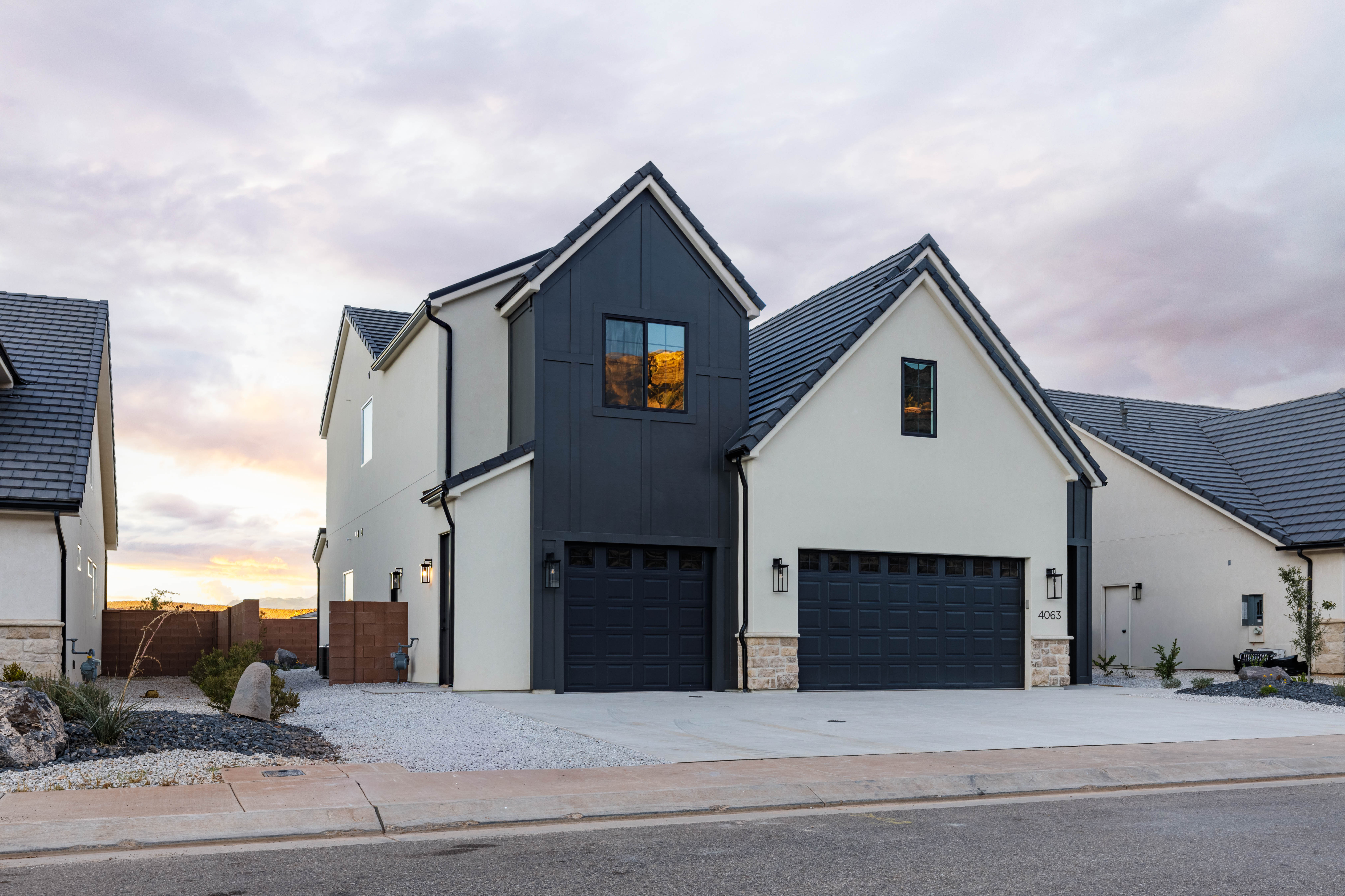 Modern farmhouse with board and batten siding, a garage, driveway, and stone siding