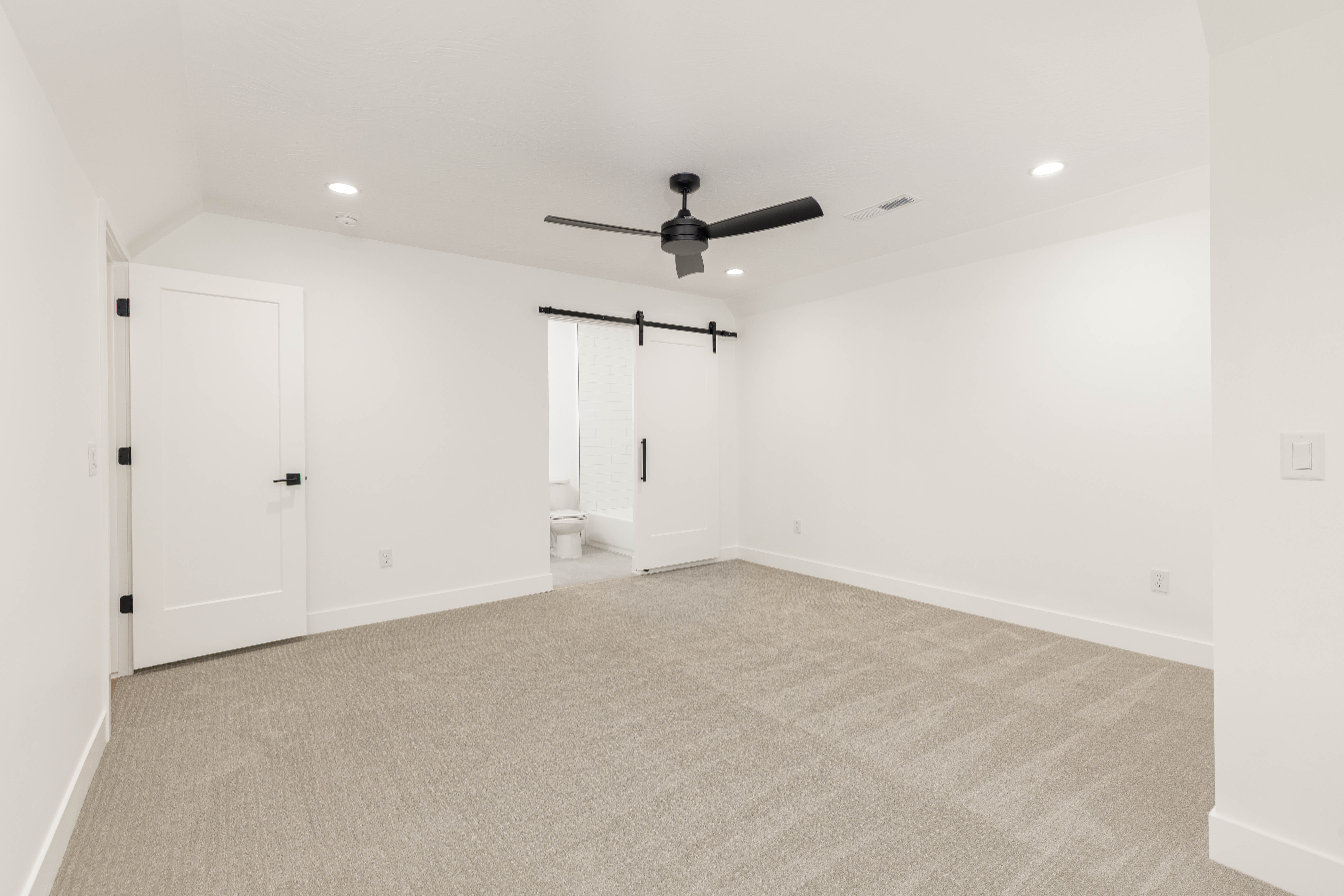 Unfurnished bedroom with recessed lighting, a barn door, ceiling fan, light colored carpet, and ensuite bathroom