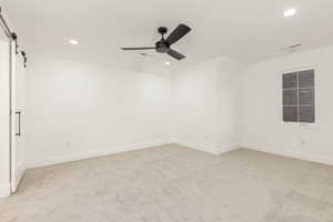 Unfurnished room with a barn door, recessed lighting, light carpet, and a ceiling fan