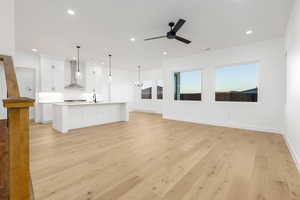 Unfurnished living room with light wood finished floors, a chandelier, recessed lighting, and ceiling fan