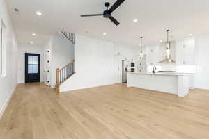 Unfurnished living room with light wood-style floors, stairs, recessed lighting, and ceiling fan