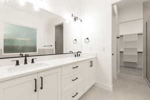 Full bathroom featuring double vanity, a stall shower, and a walk in closet