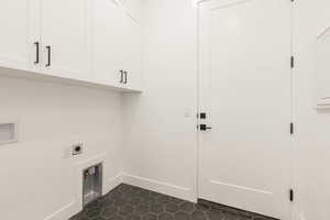 Laundry room featuring hookup for an electric dryer, cabinet space, washer hookup, and dark tile patterned flooring