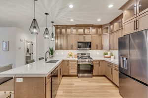 Kitchen with a kitchen breakfast bar, appliances with stainless steel finishes, glass insert cabinets, a peninsula, and recessed lighting