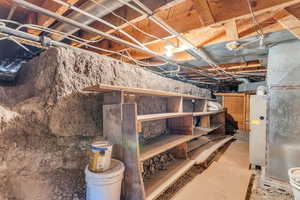 Crawl space below laundry room with newer water heater, well-maintained furnace, and dry storage area.
