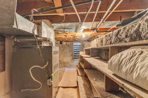 Crawl space below laundry room with newer water heater, well-maintained furnace, and dry storage area.