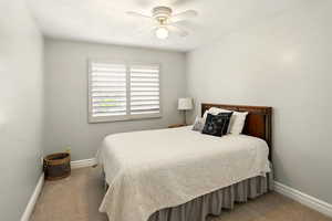 Carpeted bedroom featuring ceiling fan and baseboards